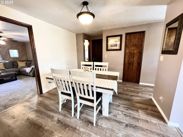 dining space featuring baseboards, a textured ceiling, dark wood-style flooring, and a ceiling fan