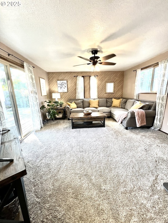 living room with a textured ceiling, carpet, ceiling fan, and wood walls