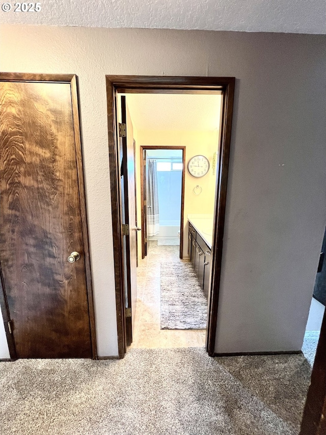 corridor featuring light colored carpet and a textured ceiling