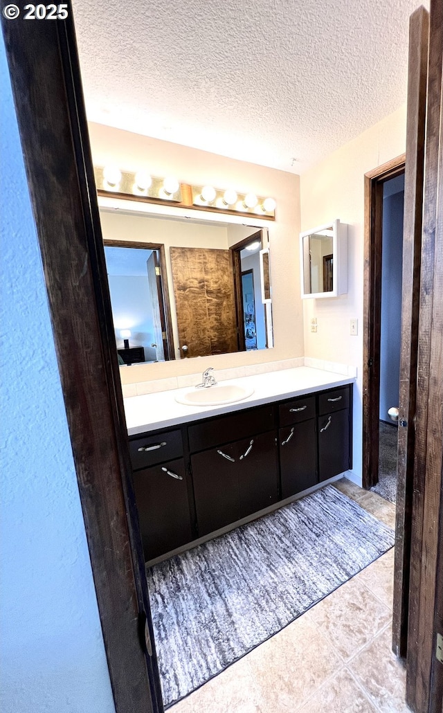 bathroom featuring tile patterned flooring, a textured ceiling, and vanity