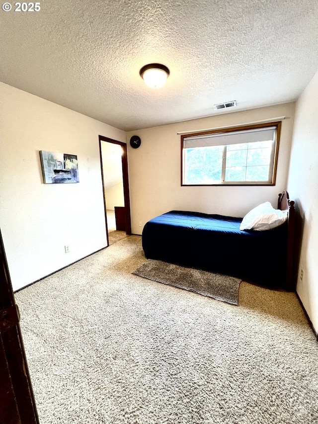 bedroom featuring visible vents, carpet floors, and a textured ceiling