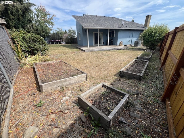 back of property featuring a garden, central air condition unit, a trampoline, a patio area, and a lawn