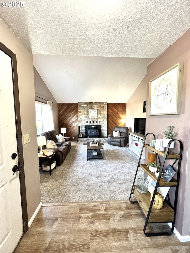 living room with lofted ceiling, wooden walls, wood finished floors, and a textured ceiling