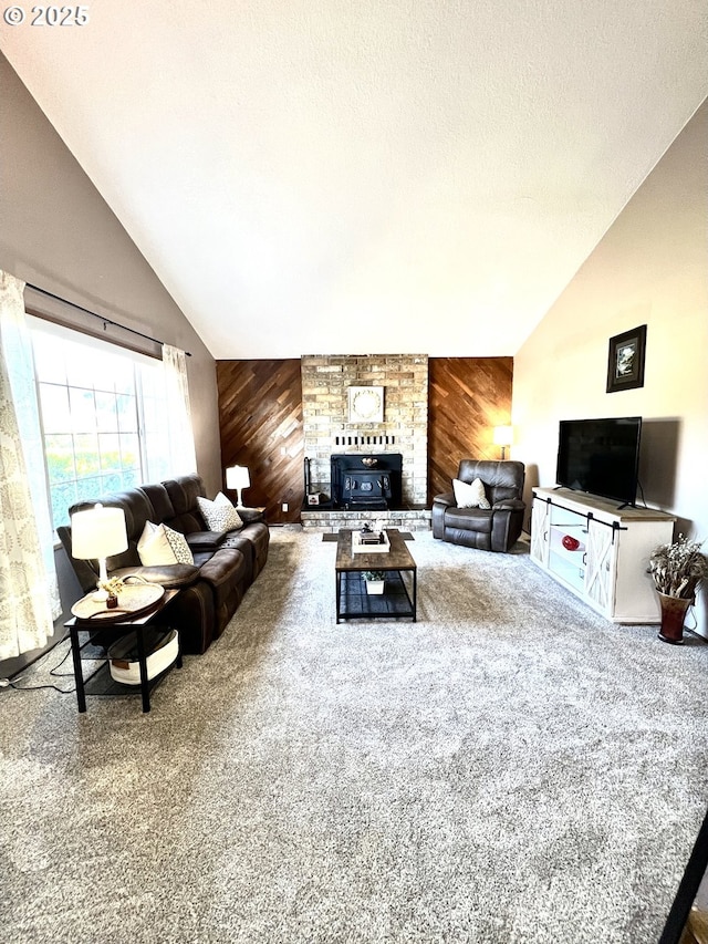 living room featuring wooden walls, a stone fireplace, vaulted ceiling, a textured ceiling, and carpet flooring