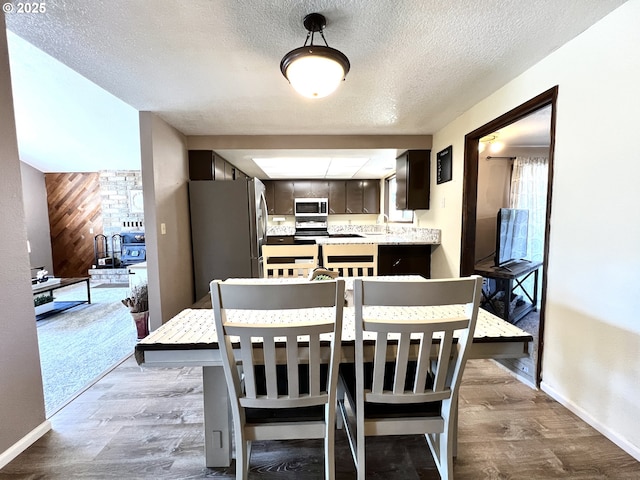 dining space featuring dark wood-type flooring, baseboards, and a textured ceiling