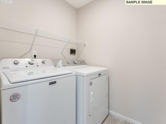 clothes washing area with light hardwood / wood-style flooring and washing machine and clothes dryer