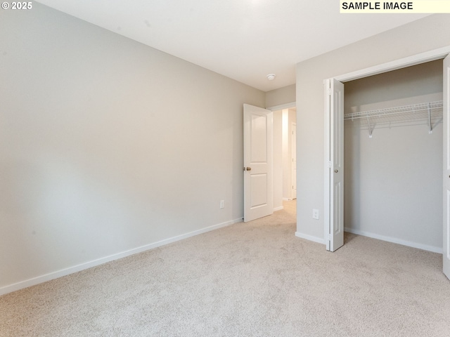 unfurnished bedroom with light colored carpet and a closet