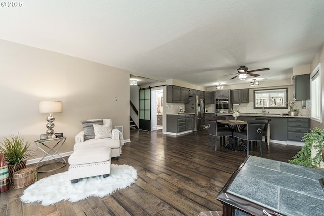 20256 S Swank Rd, Colton, OR 97017 - living room featuring a ceiling fan, dark wood-type flooring, a barn door, baseboards, and stairs