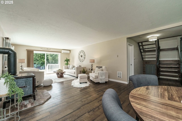 20256 S Swank Rd, Colton, OR 97017 - living area with wood-type flooring, a wall mounted air conditioner, a textured ceiling, a wood stove, and stairs