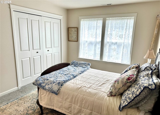 bedroom featuring a closet, visible vents, baseboards, and carpet flooring