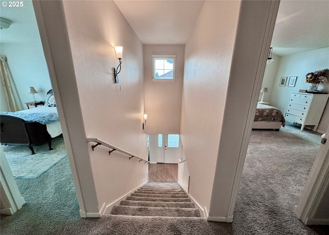 staircase with carpet, baseboards, a textured ceiling, and a textured wall