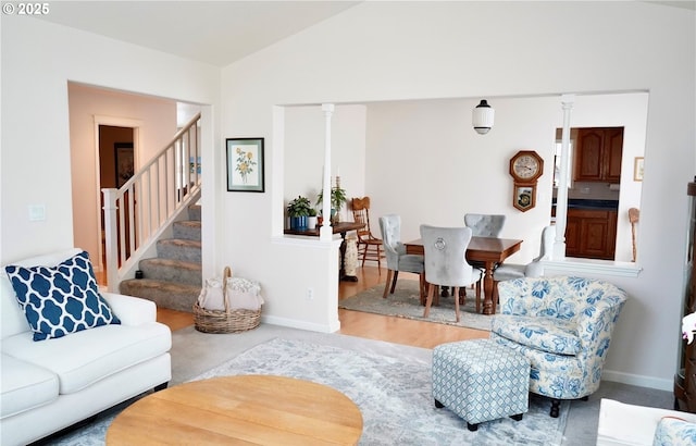 living area with ornate columns, baseboards, stairway, and vaulted ceiling