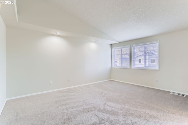 unfurnished room with vaulted ceiling, carpet flooring, and a textured ceiling