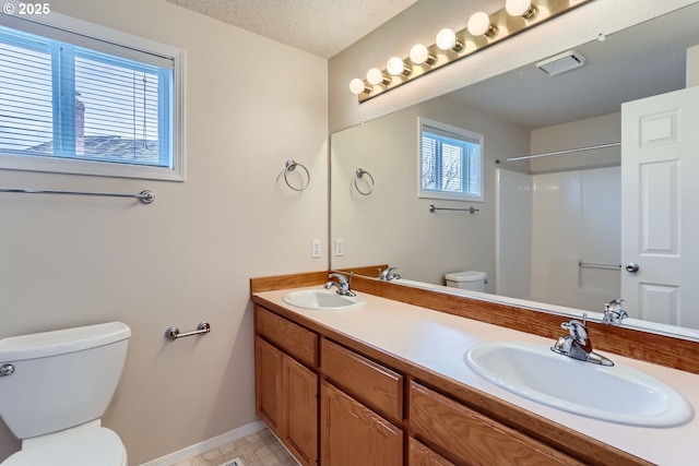 bathroom featuring vanity, toilet, a textured ceiling, and a shower