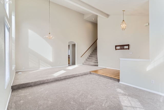 interior space featuring beam ceiling, high vaulted ceiling, carpet floors, and a chandelier