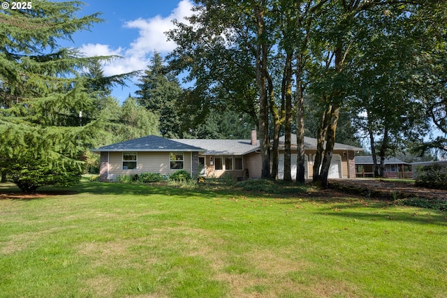 view of front of home featuring an attached garage, a chimney, and a front yard