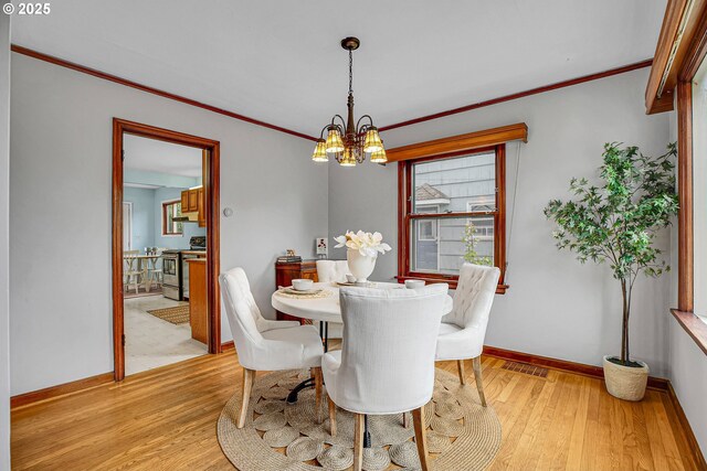 dining space with a chandelier, light wood-type flooring, baseboards, and crown molding