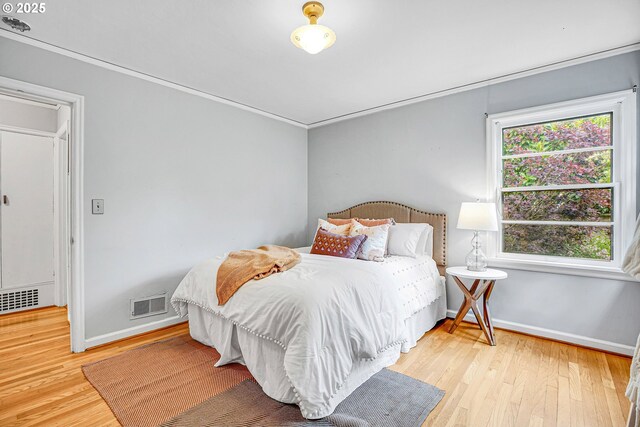 bedroom with wood finished floors, baseboards, and crown molding