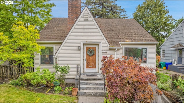 a-frame style home with fence, a chimney, and roof with shingles