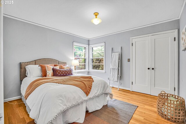 bedroom with wood finished floors, baseboards, and a closet