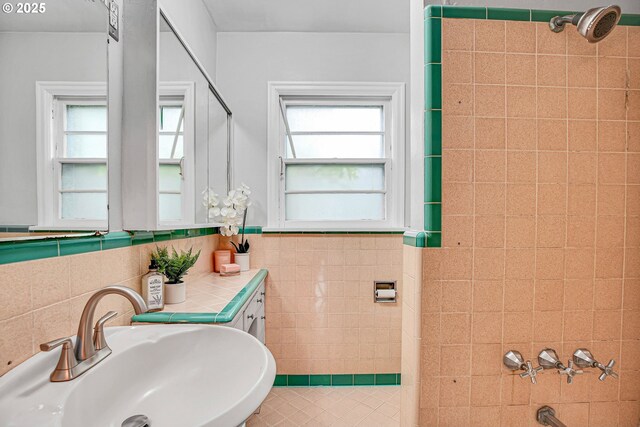 full bathroom with a sink, plenty of natural light, tile walls, a shower, and wainscoting