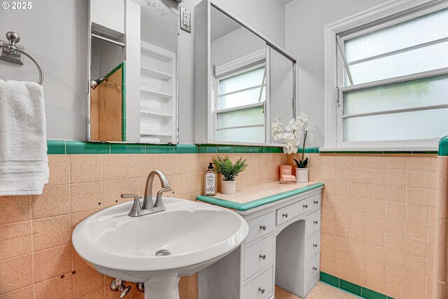 bathroom featuring a sink and tile walls