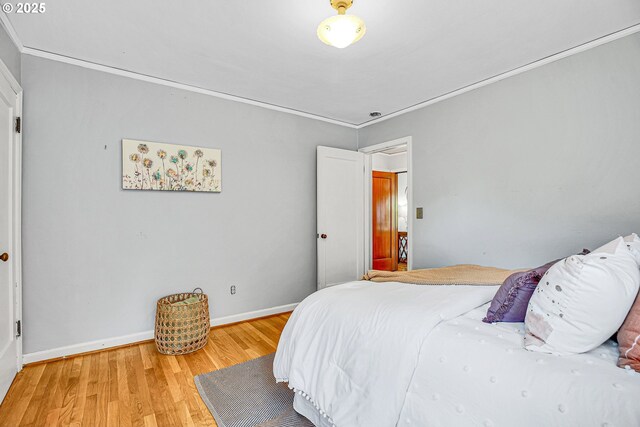 bedroom featuring light wood-style flooring, ornamental molding, and baseboards