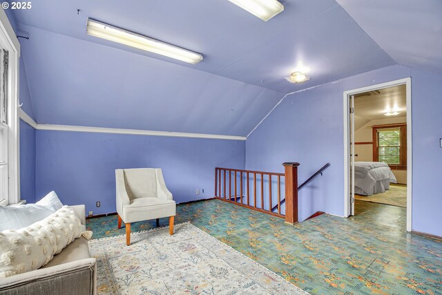 living area with lofted ceiling, carpet, and an upstairs landing
