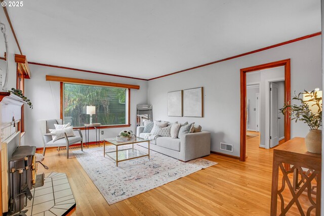 living room with light wood-style flooring, crown molding, and baseboards