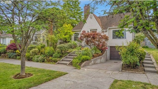 view of front of home with driveway, a garage, and a chimney
