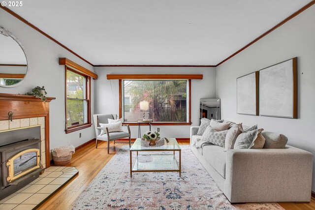 living area with crown molding, wood finished floors, baseboards, and a wood stove