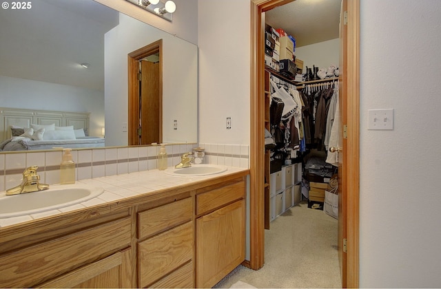 full bathroom with a sink, tasteful backsplash, a spacious closet, and double vanity
