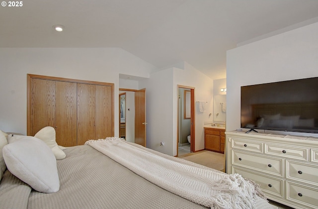 bedroom with ensuite bathroom, a closet, light carpet, a sink, and lofted ceiling