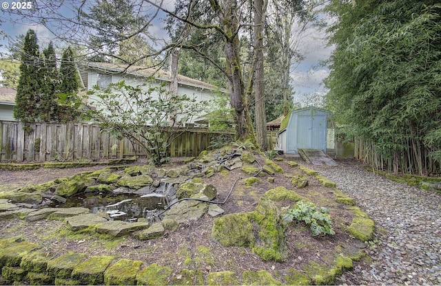 view of yard featuring fence, an outbuilding, and a storage unit