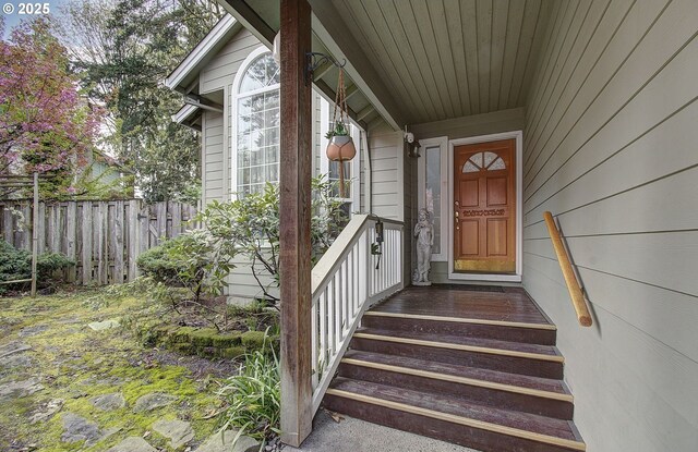 entrance to property with a porch and fence