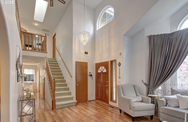 foyer with visible vents, a wealth of natural light, light wood-type flooring, and stairs