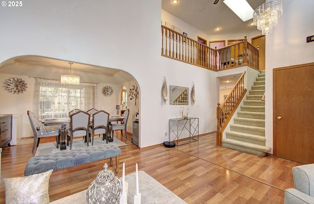 living room with arched walkways, a notable chandelier, stairs, and wood finished floors