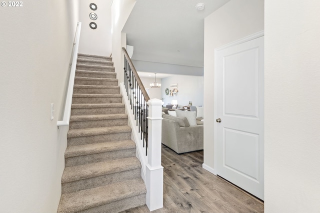 stairway with hardwood / wood-style flooring and an inviting chandelier