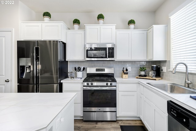 kitchen featuring tasteful backsplash, stainless steel appliances, sink, and white cabinets