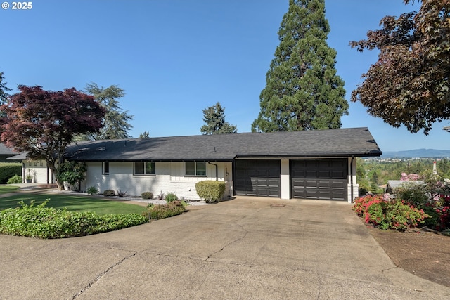 single story home with an attached garage, concrete driveway, a front lawn, and brick siding