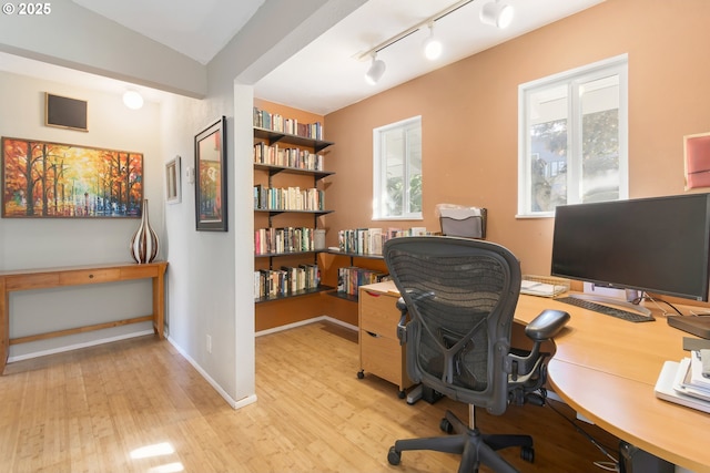 office area with baseboards, track lighting, and light wood-style flooring