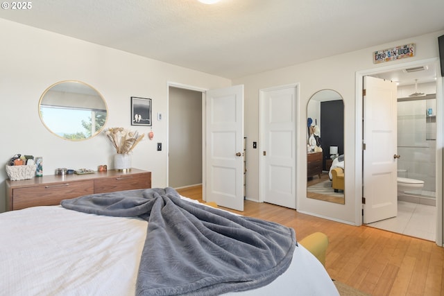 bedroom featuring visible vents, light wood finished floors, and ensuite bath