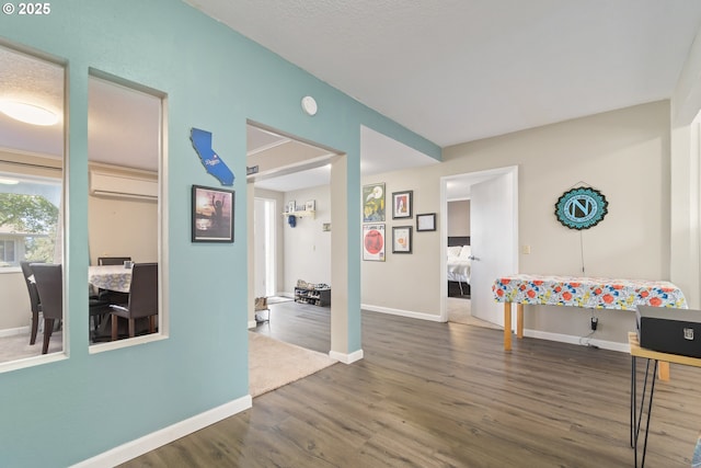 rec room featuring baseboards, wood finished floors, and an AC wall unit