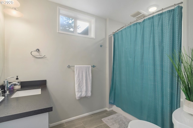 bathroom featuring wood finish floors, vanity, toilet, a shower with shower curtain, and baseboards