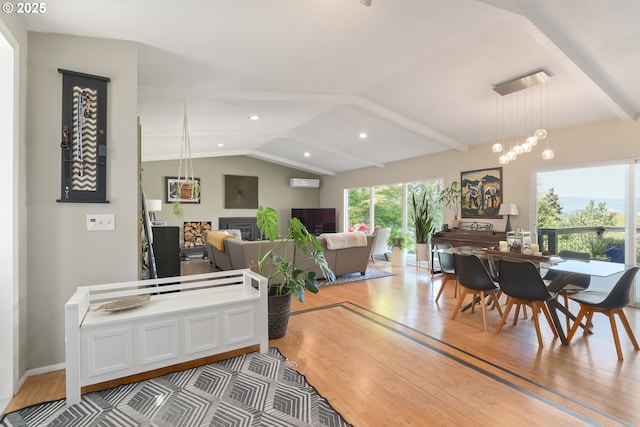 dining area with lofted ceiling with beams, wood finished floors, and a fireplace