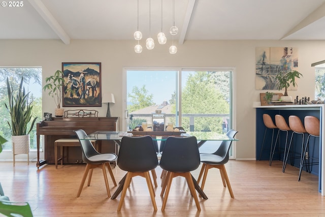 dining room with light wood finished floors and beam ceiling