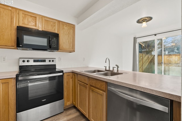 kitchen featuring sink, appliances with stainless steel finishes, light hardwood / wood-style flooring, and kitchen peninsula