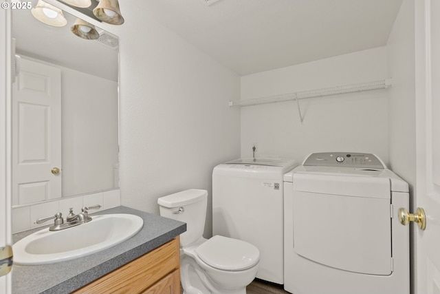 bathroom featuring toilet, washing machine and dryer, and vanity