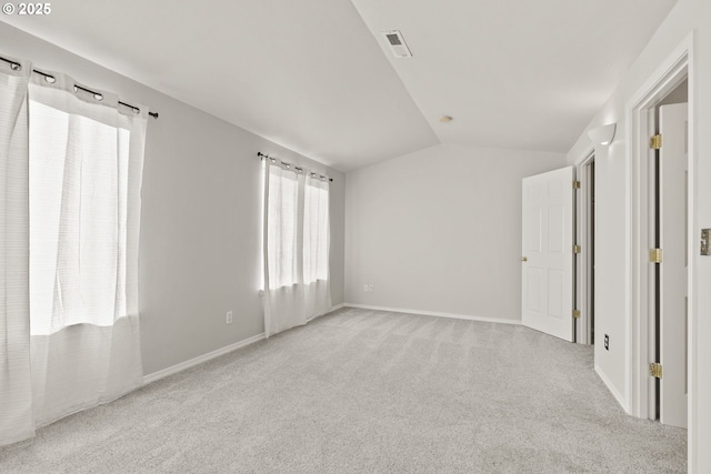 spare room with light colored carpet and vaulted ceiling