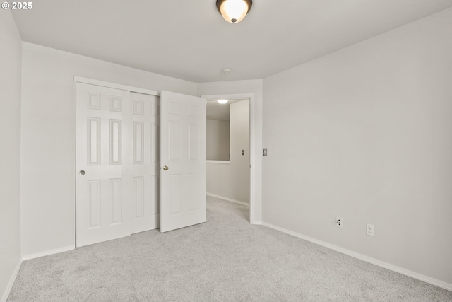 unfurnished bedroom with light colored carpet and a closet